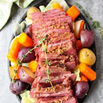 A round black plate of vegetables and sliced meat,