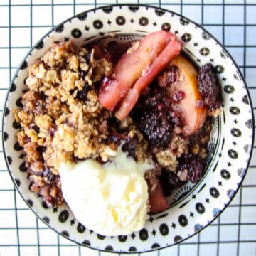 Apple and blackberry crumble in a dish on a wire rack.